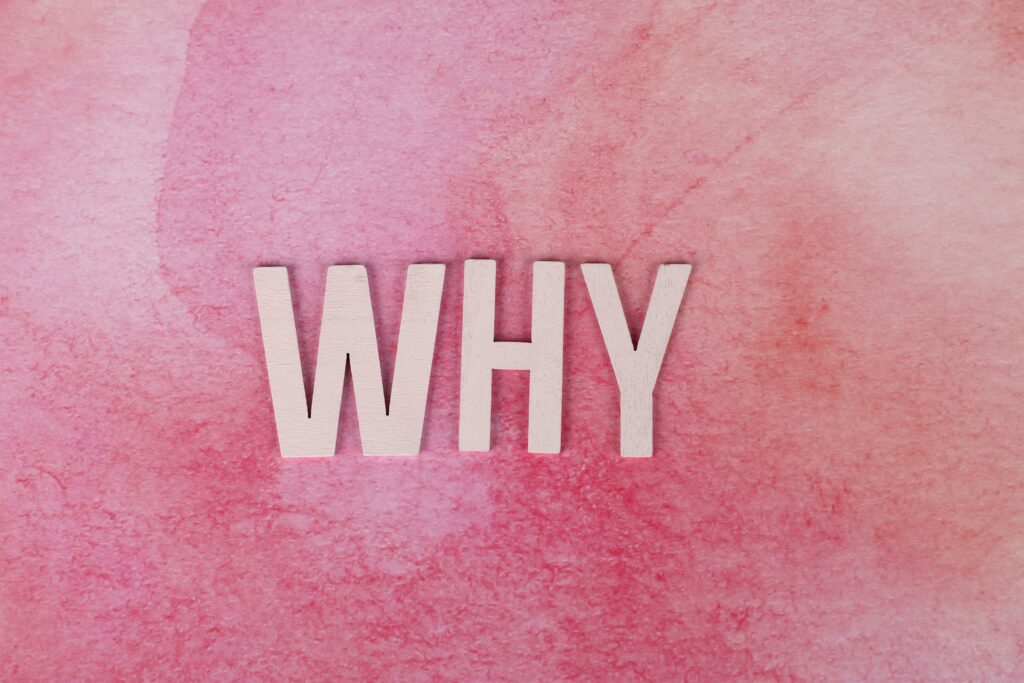 The word WHY on a pink wallpaper.