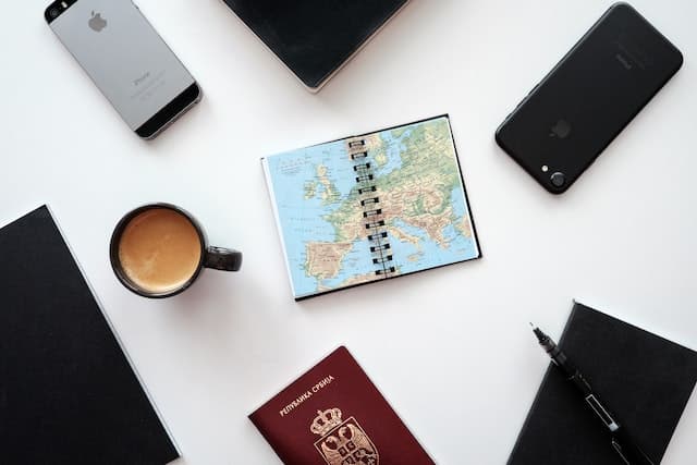 An open map, mobile phone, coffee cup, and a Serbian passport