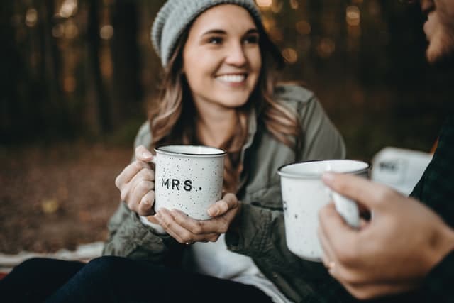A wife holding a cup and smiling as her husband learnt some of the ways to say beautiful in the Serbian language