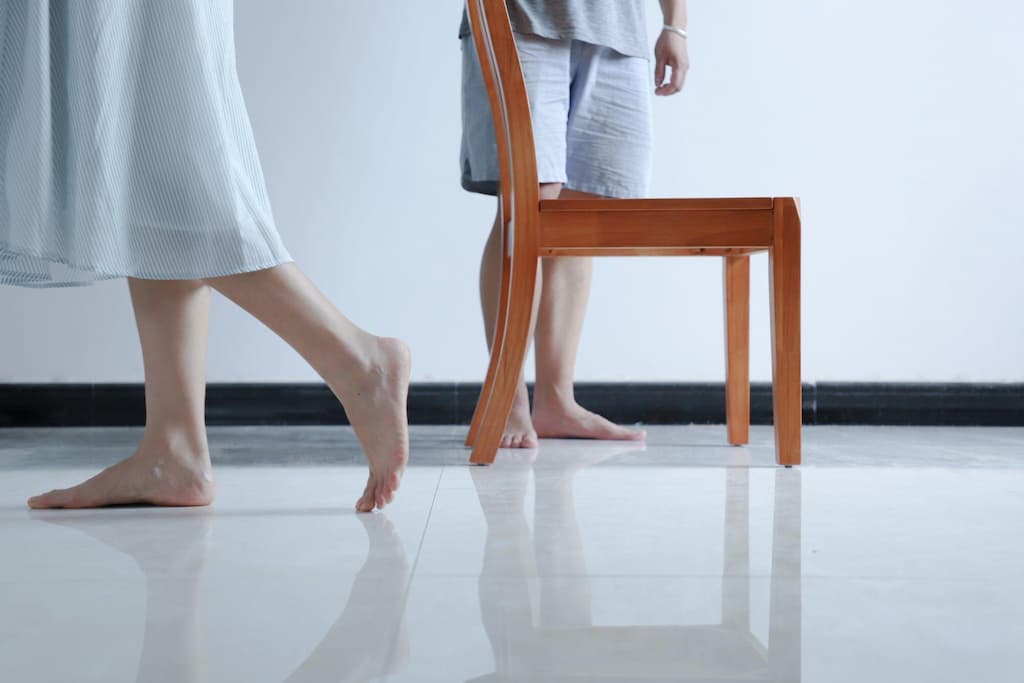 Two people walking barefoot on white tiles