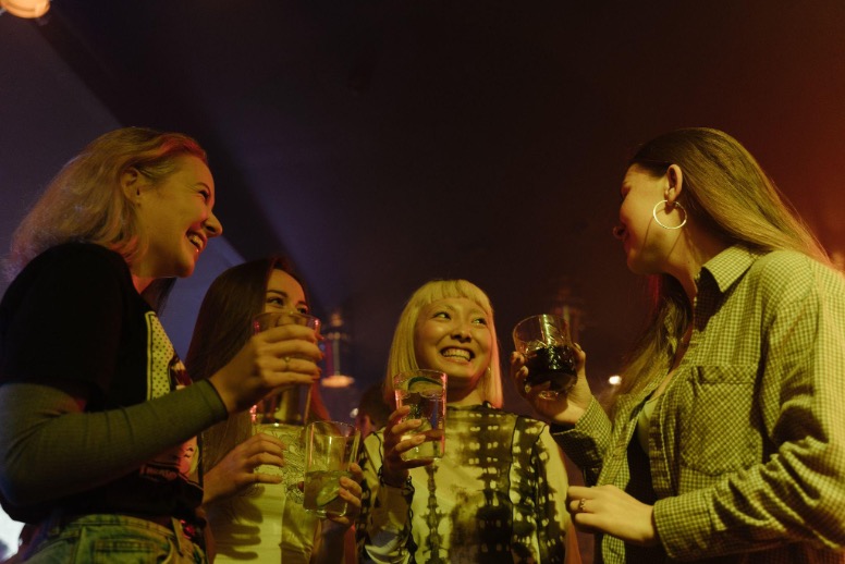 Girls holding drinks in their hands and laughing in a nightclub