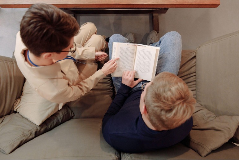 Two people sitting on a couch and reading a book