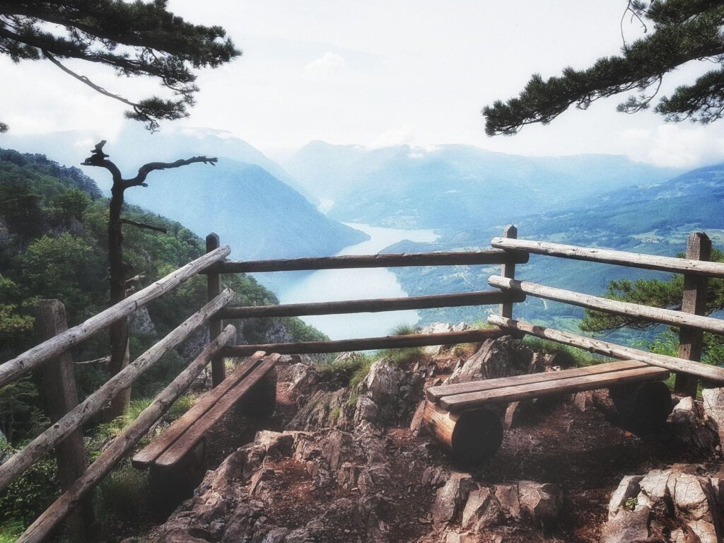A wooden bench on the top of mountain overlooking a river and a lake