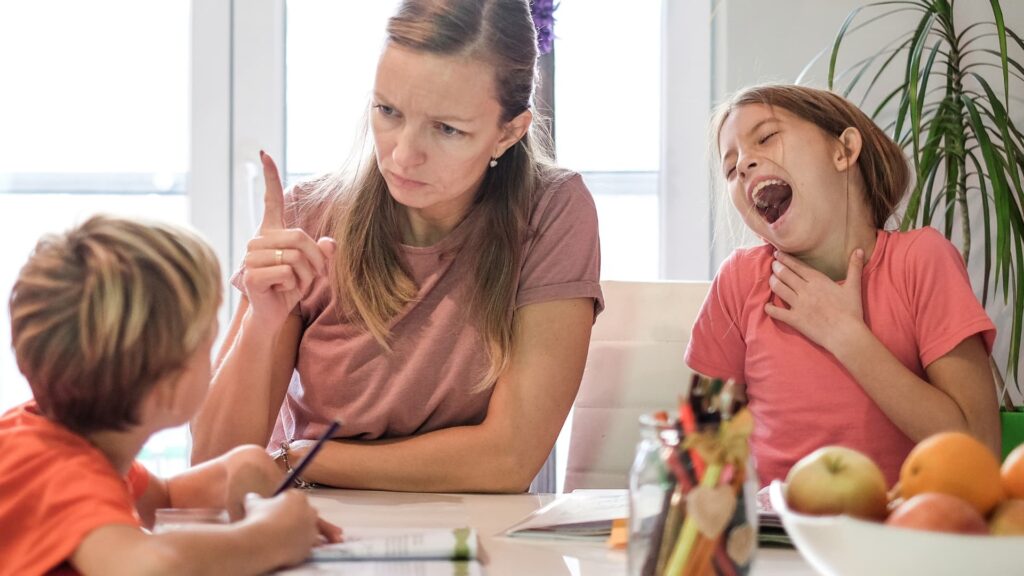 mother scolding her son while daughter is laughing