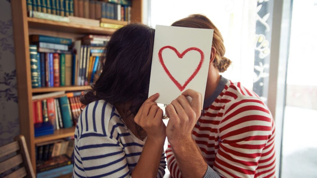 Young man and woman holding a postcard with a heart on it