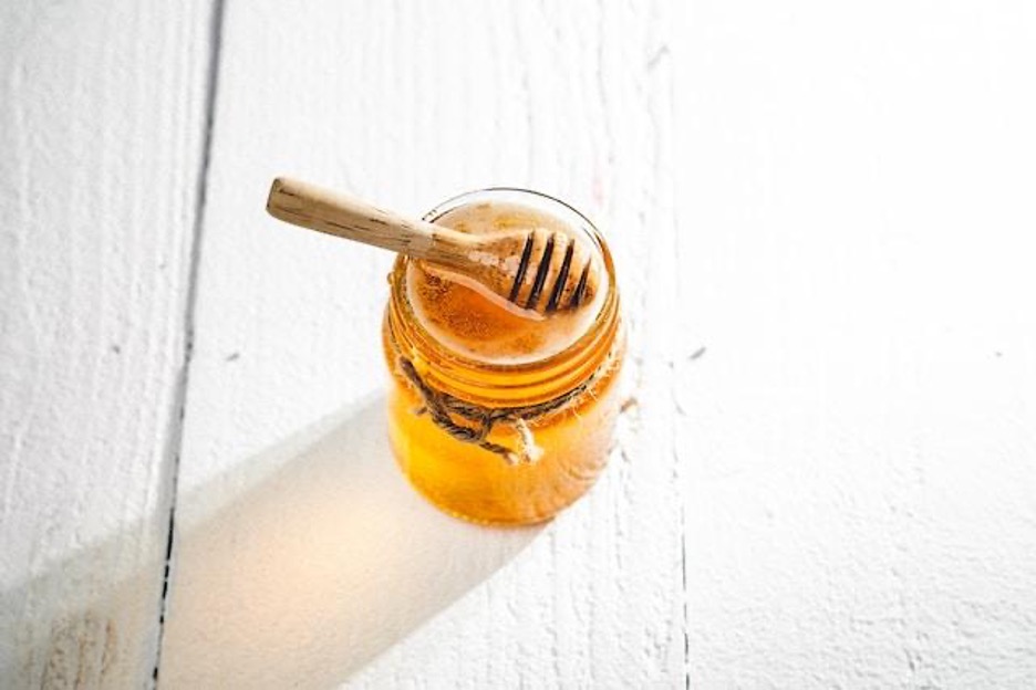 A jar of honey with a honey dipper on top