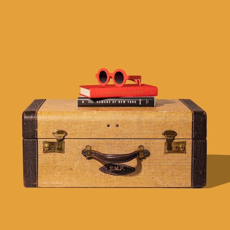 Red sunglasses and books on top of an old-fashioned suitcase.