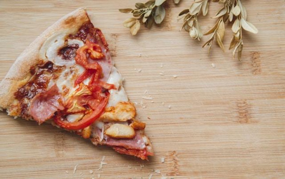 A piece of pizza on a wooden counter.