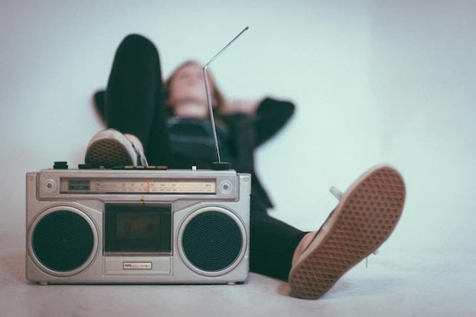 A woman lying behind an old-fashioned radio.