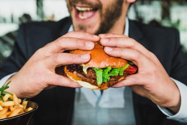 : A man holding a hamburger in front of him.