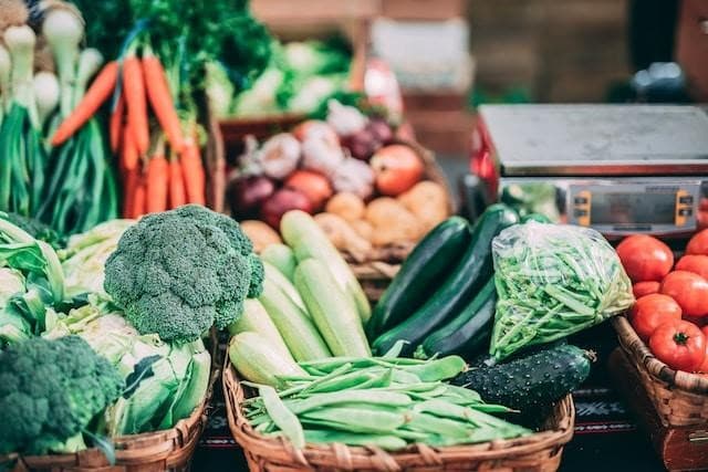 Broccoli, tomatos, carrots, and other vegetables inside of baskets.