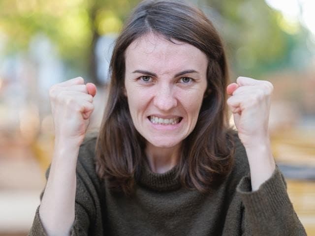 An angry-looking woman holding her fists up in the air.
