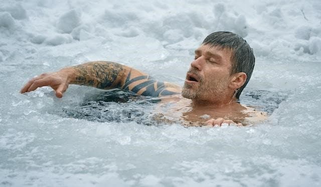 A man swimming in frozen water.
