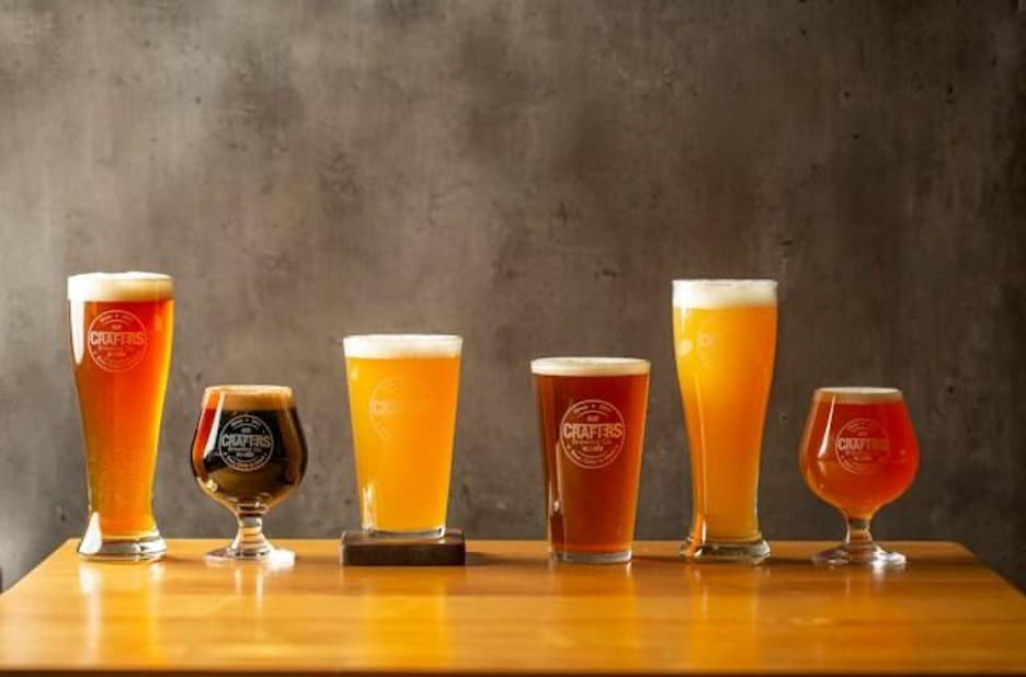 Six glasses of various sizes full of beer.