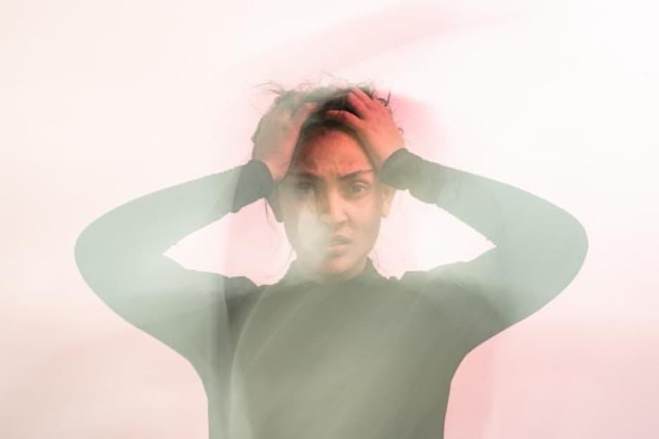 A woman holding her head looking confused.
