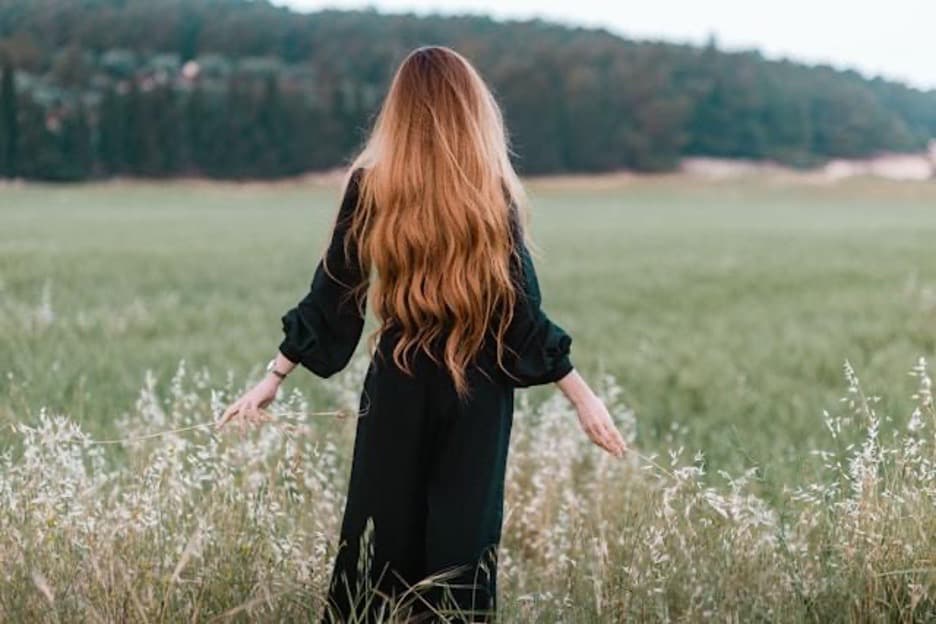 A woman standing in a green grass field.