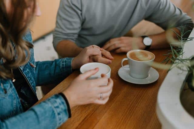 A woman holding a man's hand at a cafe.