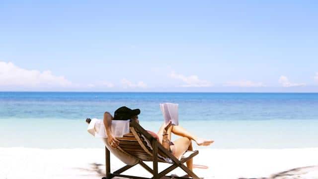 A woman reading a book at a beach.