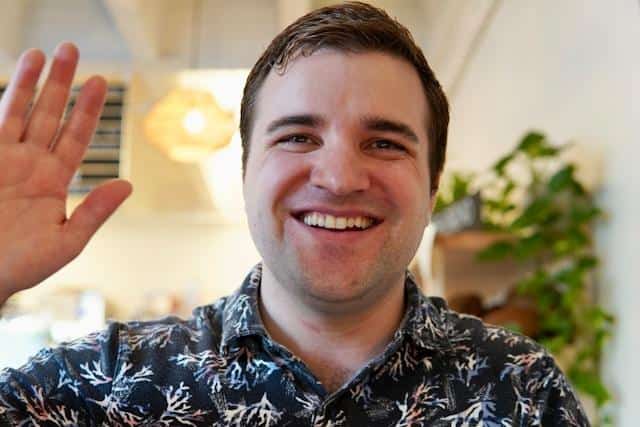 A smiling man waving goodbye.