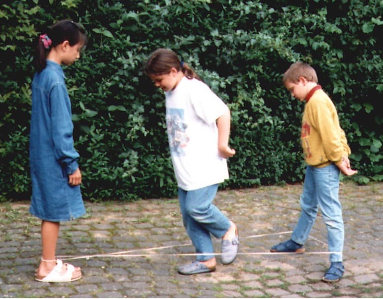 Three children playing with an elastic band — one of Serbian games for kids.