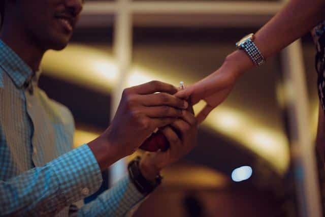 A man putting on a diamond ring on a woman's finger.