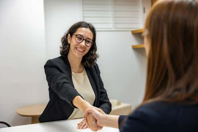 Two women shaking hands at a job interview.
