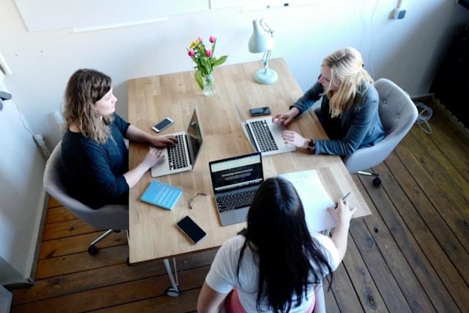 Three women in the office, sitting at the same desk.