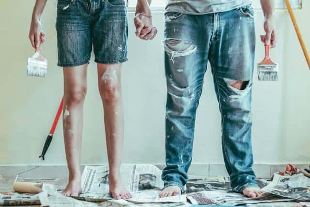 A man and a woman painting their own house walls — one of the common ways of saving money in Serbia.