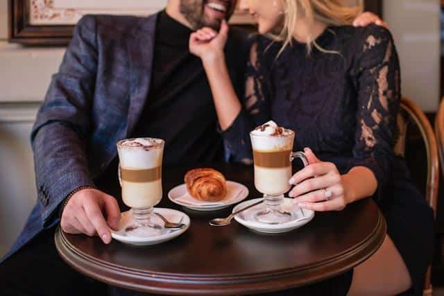 A man and a woman laughing and cuddling at a cafe.