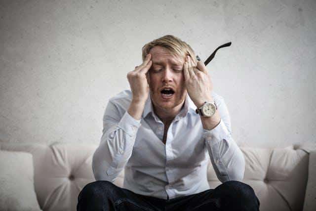 A man holding his head, looking frustrated.