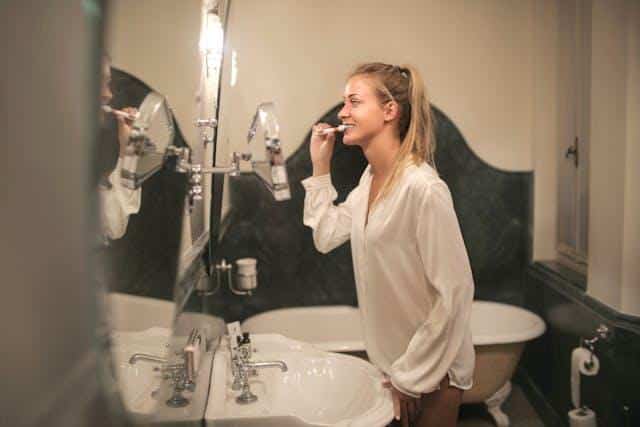A woman brushing her teeth in her bathroom.