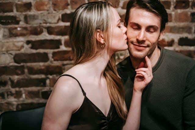 A woman kissing a man on the cheek.