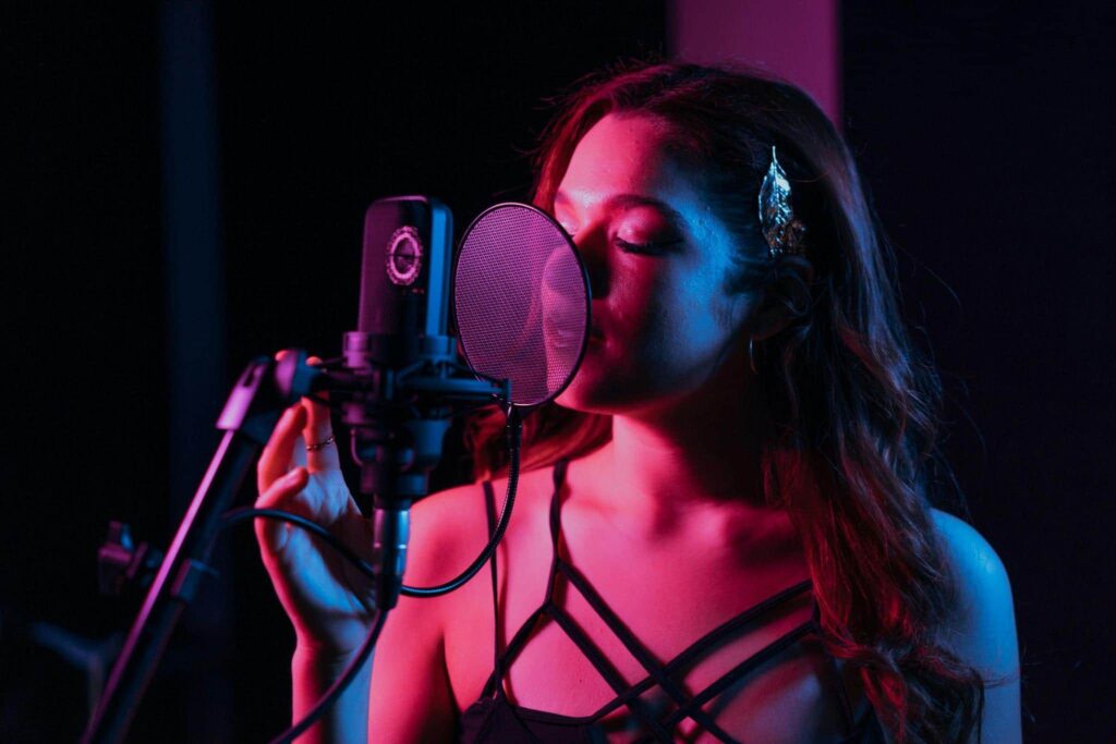 A pretty woman singing with her eyes closed.