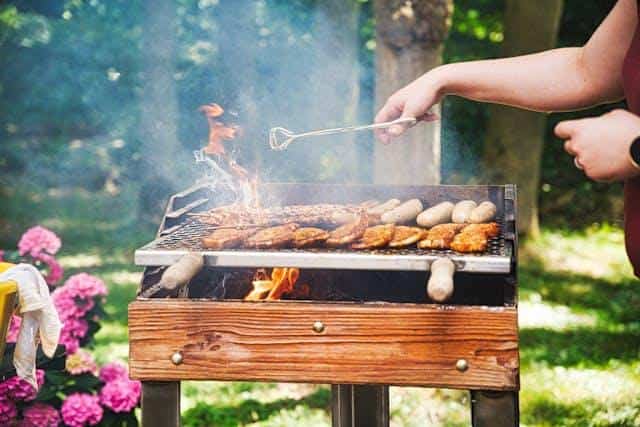 A person grilling meat in nature.