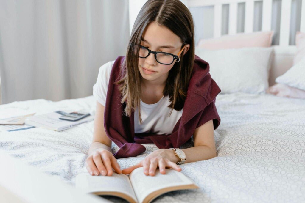 A woman lying on the bed studying the Serbian preposition za.