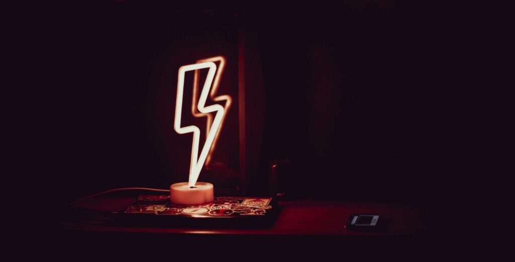 Glowing neon lamp in the shape of lightning in a dark room.