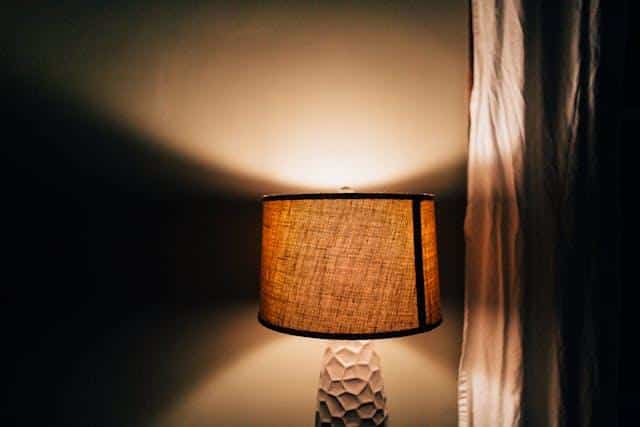 A switched-on table lamp in a dark room symbolizing everyday electricity powered by Serbian inventions.