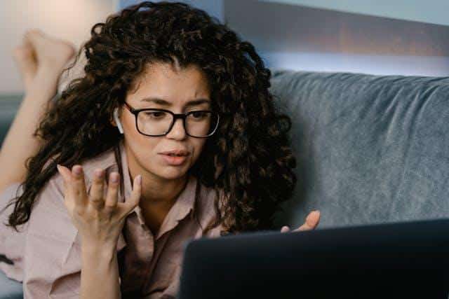 A woman looking at a laptop, with a confused expression while trying to figure out the mistakes English speakers make in Serbian.
