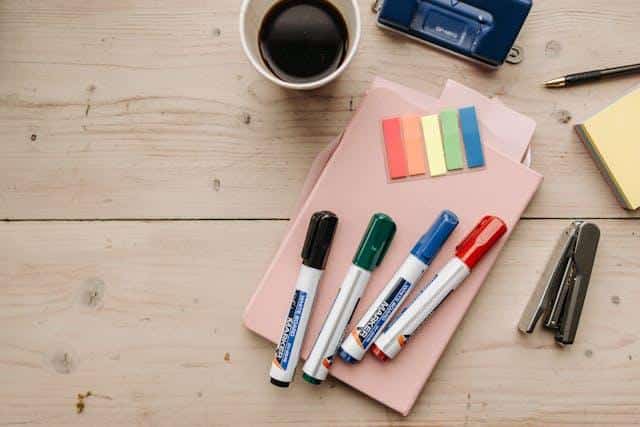 Desk setup with notebook, sticky notes, and markers for practicing Serbian at home.