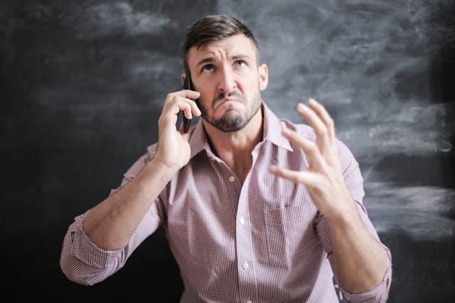 A man talking on the phone with an angry look on his face.