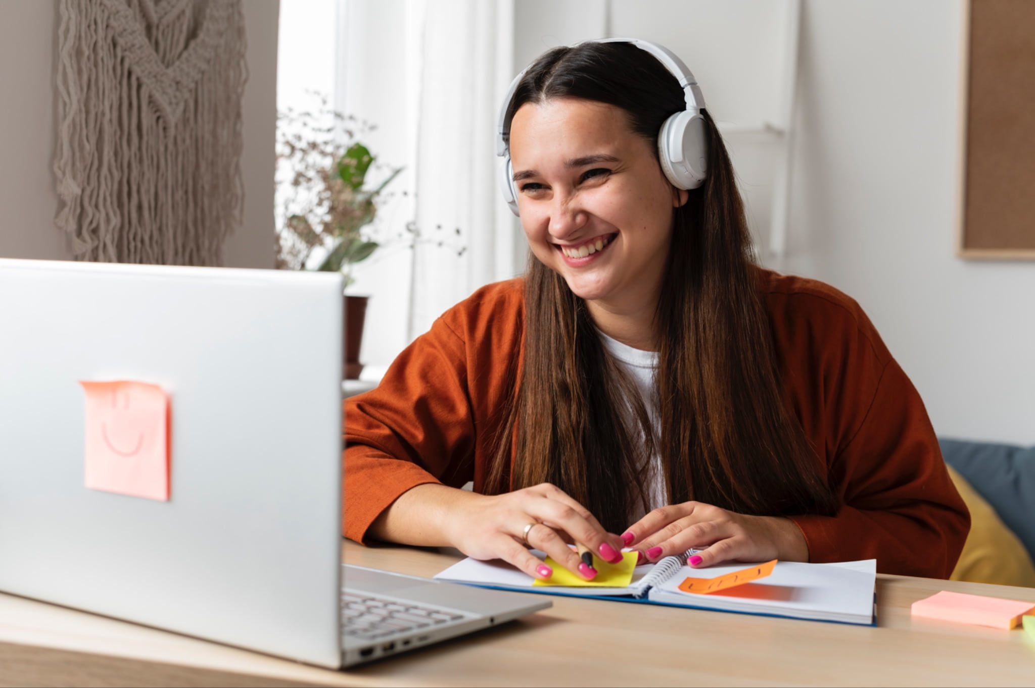 A woman wearing headphones smiling at her laptop